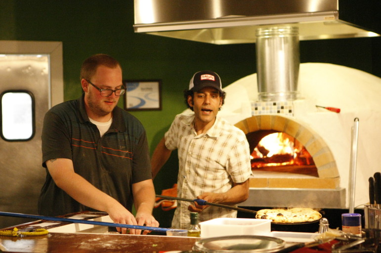 Muhammad Alhawagri pulls a pizza out of the oven at A Pizza Story.
