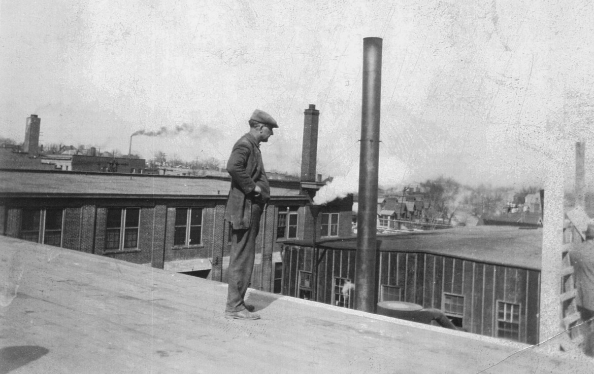 An unidentified man standing on the roof of the current mill building.  he is apparently looking at the scaffolding being used to construct the chimney which was thoughtfully saved during restoration.  the original tar paper covered mill building can still be seen as can the Saratoga Lanes building.