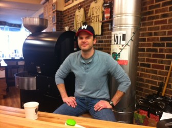 Jamie Jeschke of La Cosecha Coffee at the counter. Their roaster is behind him.
