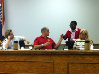 Alderman Andy Leahy give a ballot to City Manager Bola Akande.