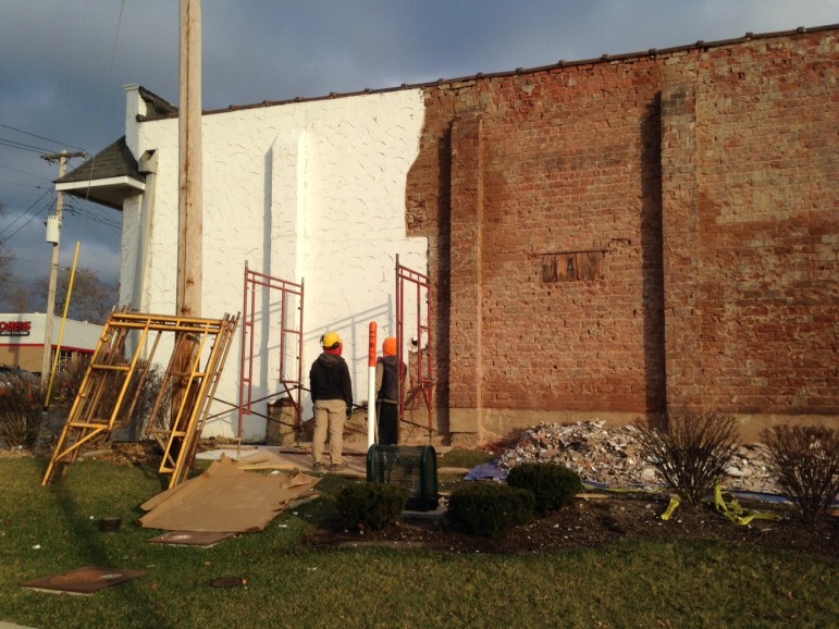 Workers chip the outer covering off the brick building on Thursday.