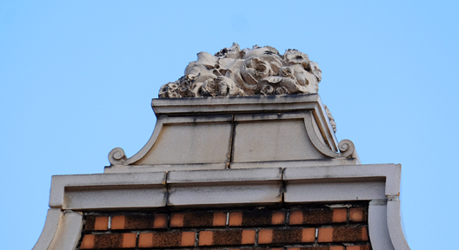 I think these must be terra cotta flowers sitting on the parapet coping.