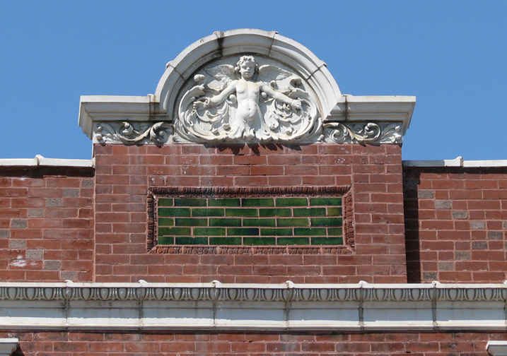 This atop the parapet of our first City Hall building on Sutton. the baby has wings so it must be a cherub, I suppose. I haven't the faintest idea what an ornament like this could signify. cherubs have been around at least since the baroque period (look it up. I can't do everything for you).