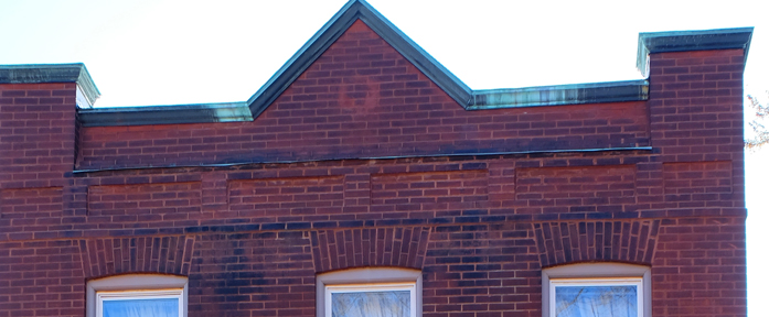 facade which faces Sotuh Street on the north has some nice robust brick arches over the windows. It even still has wht I would guess might be an original copper cap on the parapet. Look closely and you can see a ghost of something circular that was once hanging in the center.